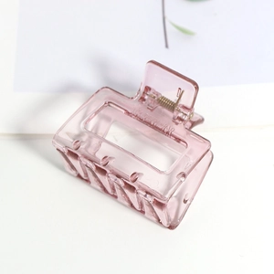 Gros plan d'une pince à cheveux rectangulaire rose mat avec un ressort en métal doré