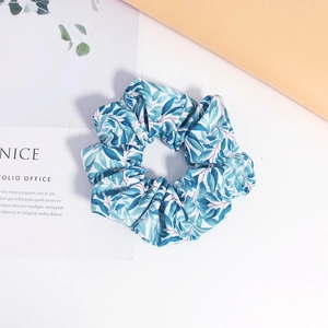 Détail d'un chouchou en tissu avec imprimé floral de feuilles bleues sur coton blanc