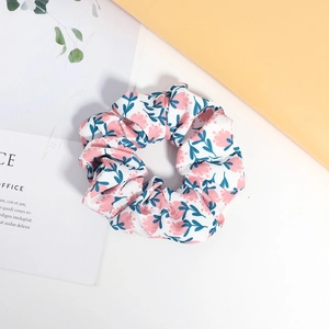 Chouchou en tissu imprimé floral avec fleurs roses et feuilles vertes sur fond blanc