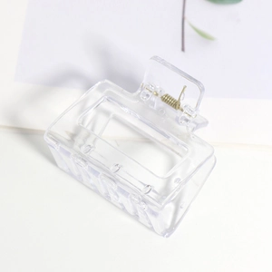 Détail d'une pince à cheveux carrée transparente mate avec ressort métallique doré