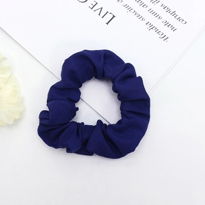 Détail d'un chouchou en tissu plissé bleu foncé sur un fond blanc élégant et fleuri