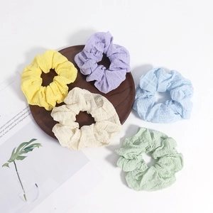 Lot de 5 chouchous en seersucker aux couleurs pastel sur un plateau en bois