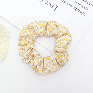 Floral print cotton scrunchie with yellow flower pattern on a beige background