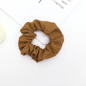 Vue détaillée d'un chouchou en tissu marron foncé avec texture sergé sur fond minimaliste