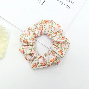 Macro shot of white fabric scrunchie with delicate orange and pink floral pattern print