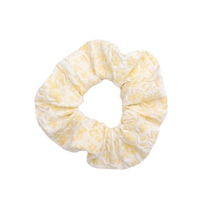 Chic floral scrunchie hair tie with creamy yellow flower pattern on a white fabric