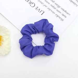 Détail d'un chouchou en tissu violet foncé avec texture plissée douce et bande élastique