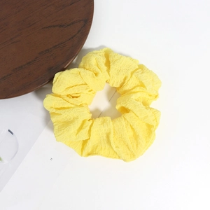 Vue détaillée d'un chouchou jaune vif en seersucker avec une texture gaufrée douce