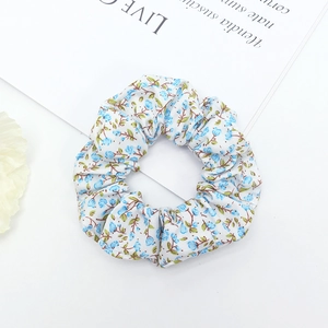 Detail shot of a floral print scrunchie with blue small flowers and pleated soft fabric texture