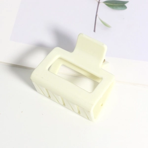 Vue détaillée d'une pince à cheveux carrée crème avec une finition mate et design creux
