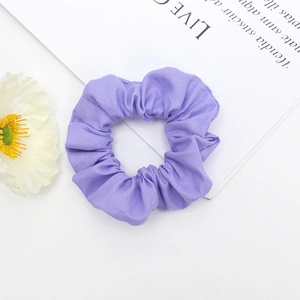 Vue détaillée d'un chouchou en tissu violet aux plis souples sur un bureau épuré