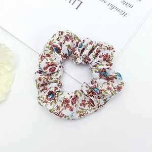 Detailed macro view of white floral fabric scrunchie with red and blue flower patterns