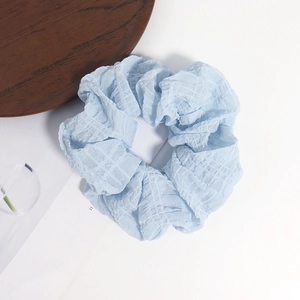 Chouchou bleu clair en tissu seersucker gaufré pour femmes sur fond blanc épuré