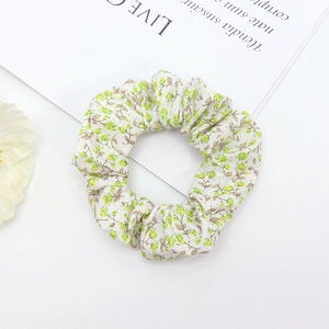 Detailed view of floral scrunchie with green and yellow patterns on a fresh background