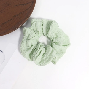 Gros plan d'un chouchou vert clair en tissu gaufré avec détail de texture élastique
