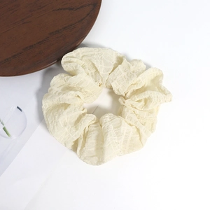Détail du chouchou crème à carreaux avec texture de tissu doux et bande élastique