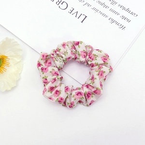 Top view of a floral pink fabric scrunchie on a white background with decorative card