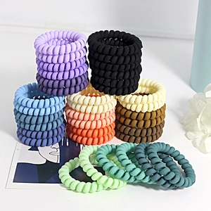 Matte telephone cord hair ties in assorted colors on a minimalist white surface