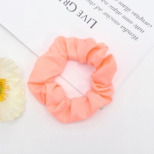 Texture détaillée d'un chouchou en tissu orange pêche vif sur un fond blanc pur