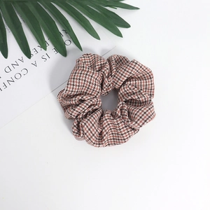 Detailed close-up of brown houndstooth fabric scrunchie with soft pleated texture
