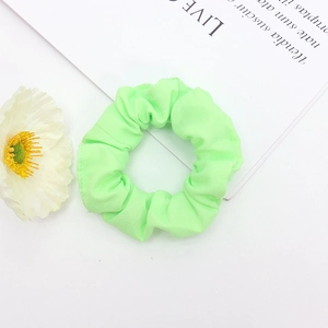 Gros plan d'un chouchou en tissu vert citron avec bande élastique sur fond blanc
