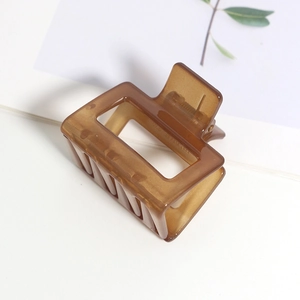 Détail d'une pince à cheveux en résine ambre avec un design de cadre rectangulaire évidé