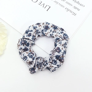 Detailed macro view of white fabric scrunchie with blue and brown floral patterns