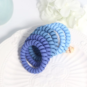 Set of 5 matte blue gradient spiral hair ties displayed in a decorative white dish