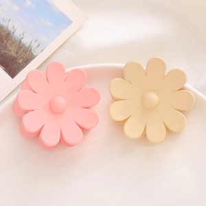 Gros plan de pinces à cheveux marguerite rose et crème avec texture mate sur une assiette