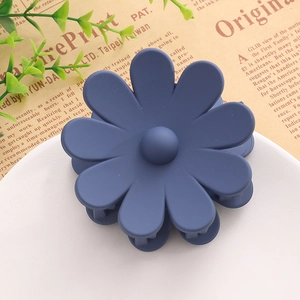 Détail d'une pince à cheveux marguerite bleu marine mat sur un fond vintage