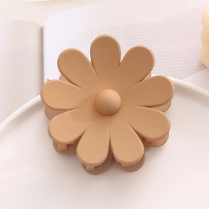Gros plan d'une pince à cheveux fleur de marguerite mate beige crème sur fond neutre