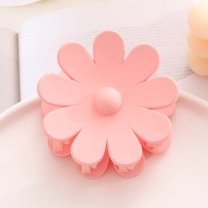 Vue détaillée d'une pince à cheveux fleur rose mat sur un support décoratif élégant