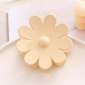 Vue détaillée d'une pince à cheveux fleur mate de couleur crème sur un plateau