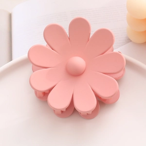 Gros plan d'une pince à cheveux fleur rose sur un plateau blanc avec décoration