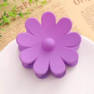 Gros plan d'une pince à cheveux fleur violette mate sur un fond de papier décoratif
