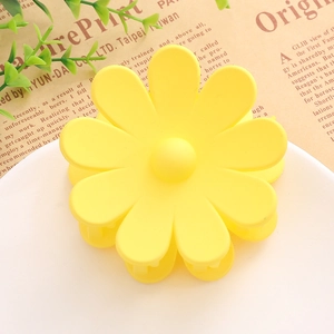 Détail d'une pince à cheveux mate en forme de marguerite jaune sur un plateau décoratif