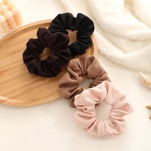Set of four vintage corduroy hair scrunchies in black brown khaki and pink on wooden tray