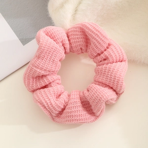 Close-up of pink knitted scrunchie showing the soft waffle texture and elastic fabric detail