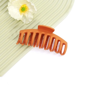 Détail macro d'une grande pince à cheveux orange mat avec dents emboîtables