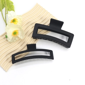 Matte black large rectangular and curved hair claws set on a beige textured plate