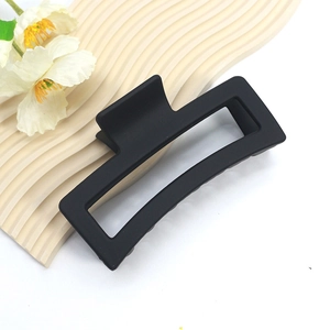 Matte black oversized rectangular shark hair clip for women on artistic wavy backdrop
