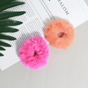 Dettaglio di elastici per capelli in peluche rosa e arancione su sfondo minimalista