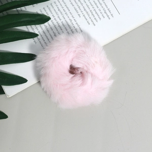 Dettaglio ravvicinato di un elastico per capelli in peluche rosa su sfondo decorativo