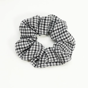 Close-up detail of the classic black and white houndstooth pattern on the fabric scrunchie
