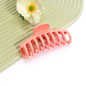 Vue détaillée d'une grande pince à cheveux orange corail mat avec design à dents courbées