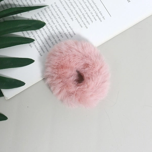 Dettaglio di un elastico per capelli in finta pelliccia rosa su sfondo decorativo