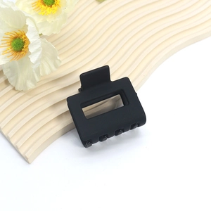 Detail shot of a large matte black square hair claw clip on a decorative display wave board