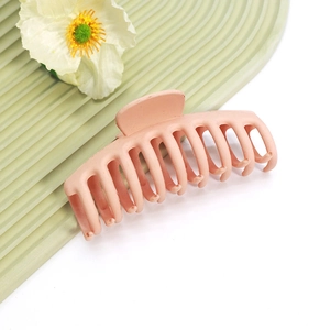 Gros plan d'une grande pince à cheveux mate rose poudré sur un fond décoratif ondulé élégant