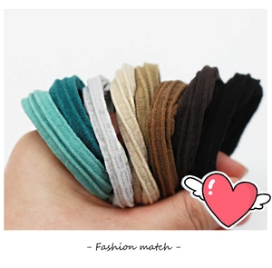 Close-up of hand holding a set of six multi-colored seamless elastic hair bands