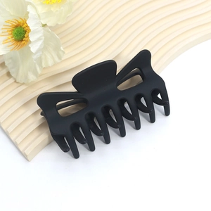 Close-up of matte black butterfly hair claw clip with cutout design on wavy display